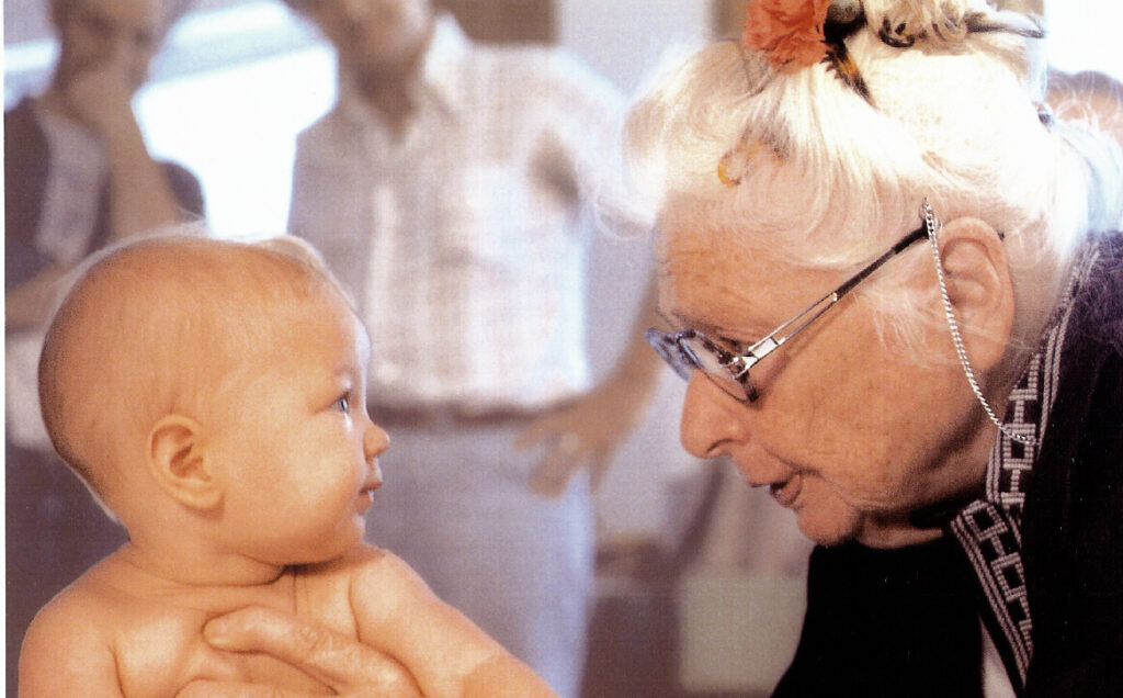 an elderly woman looking at a baby
