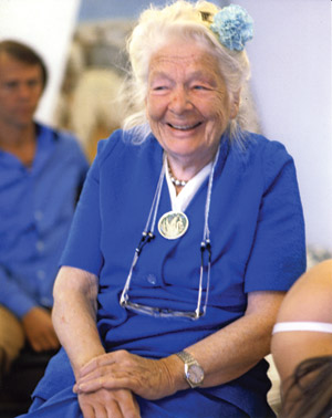 an elderly woman in a blue dress is smiling